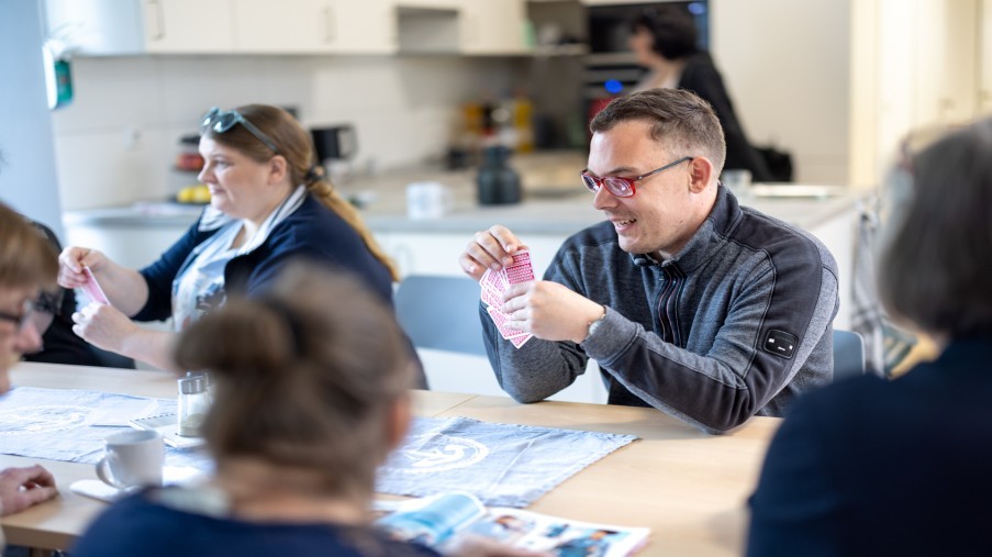 Gemeinsames Kartenspielen mit Mitarbeitenden und Kund*innen.