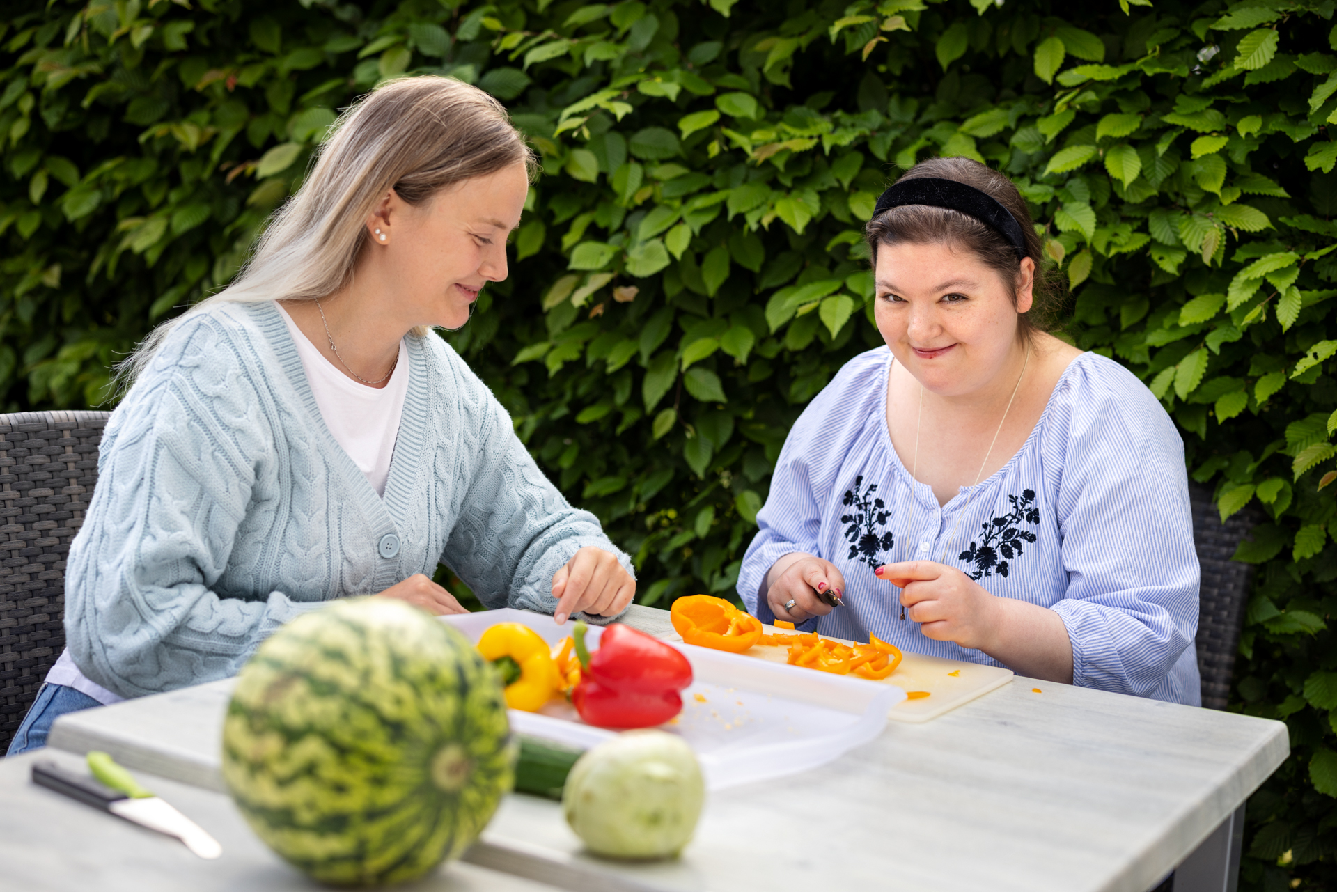Hier wird im Garten als tagesstrukturierendes Kochangebot durchgeführt. Auf dem Tisch liegen Messer und Brettchen sowie Obst und Gemüse.