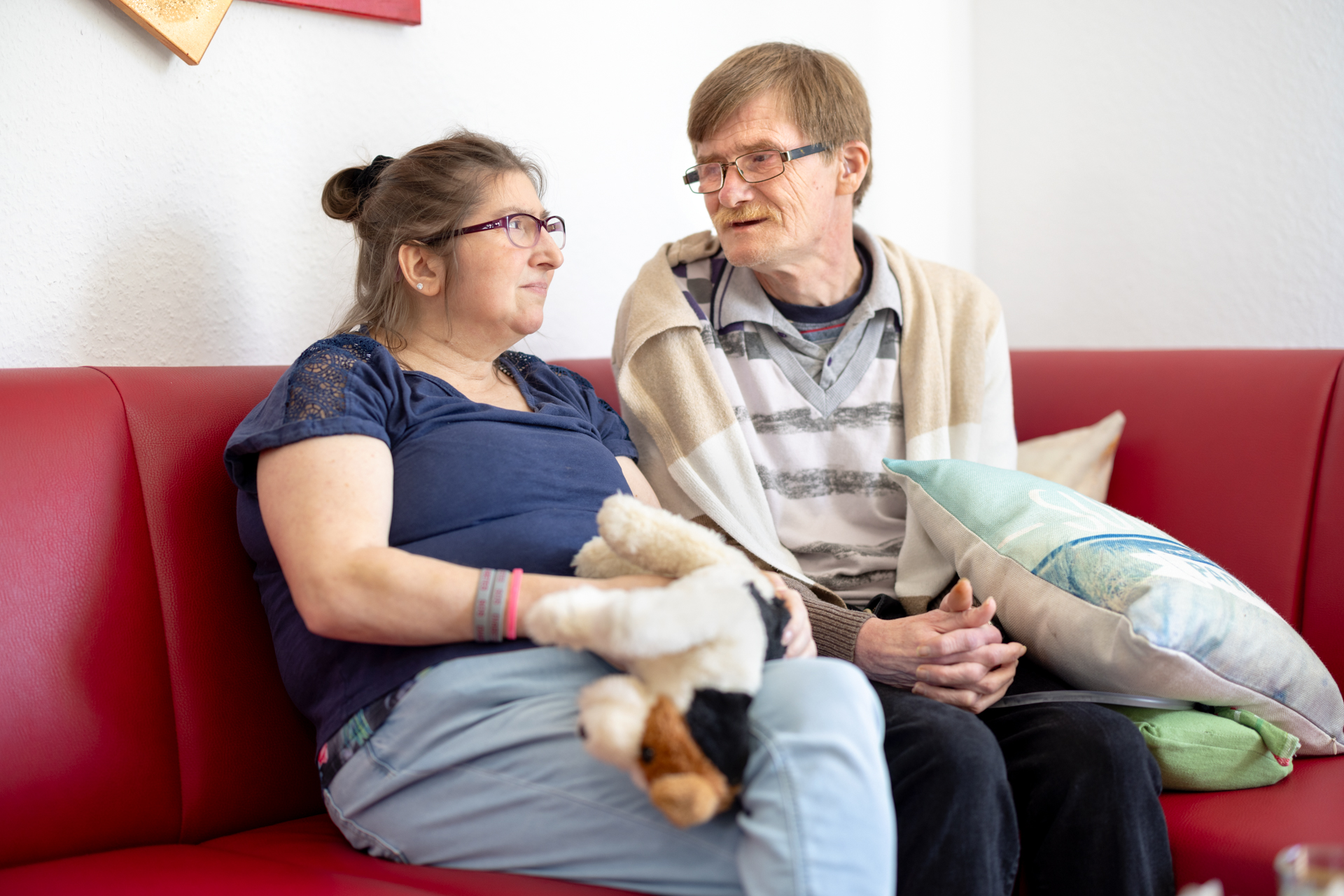 Zwei Menschen sitzen auf einem Sofa und reden mit einander. Sie nutzen beide ein Wohnangebot des LVR-Verbundes.