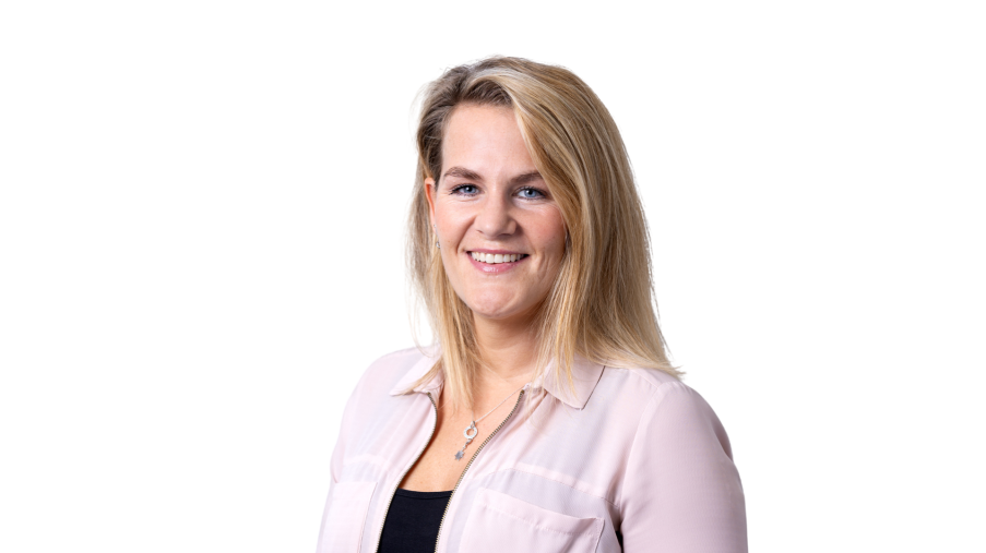 Porträt von einer Frau mit langen blonden Haaren und rosa Bluse, die in die Kamera lächelt.