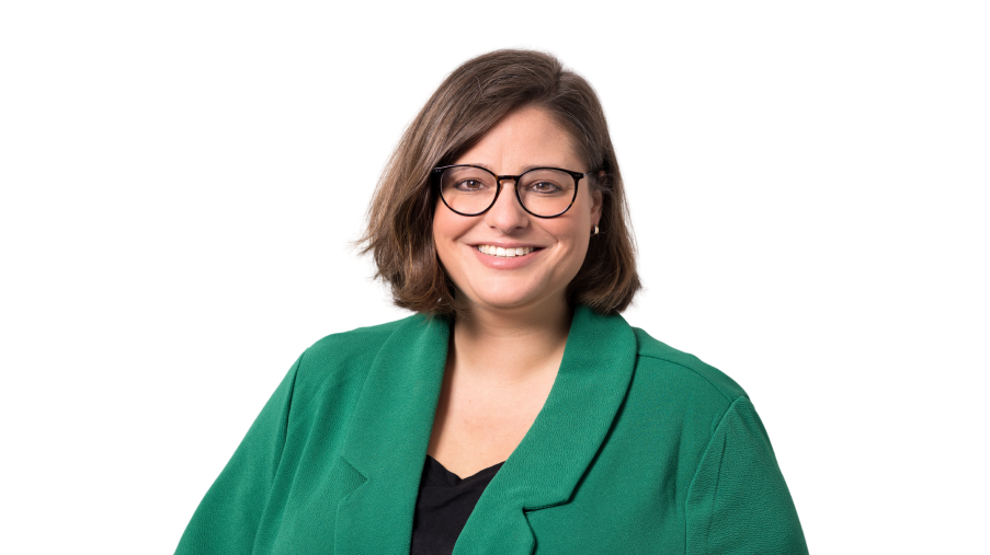 Regionalleitung Sarah Casertano, lächelnd mit Brille und grünem Jackett vor einem hellen Hintergrund