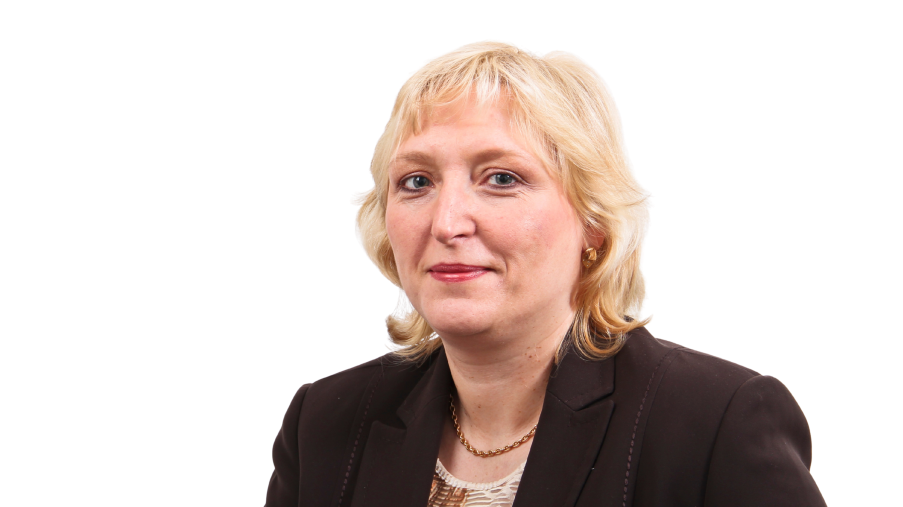 Regionalleitung Petra Schilling mit dunklem Jackett vor einem hellen Hintergrund