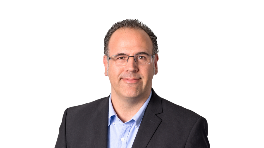 Regionalleitung Stefan Stahmann lächelnd mit Brille und dunklem Jackett vor einem hellen Hintergrund