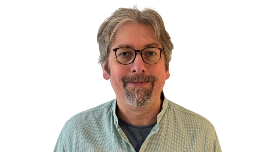 Regionalleitung Wolfgang Strubel, lächelnd mit Brille und grün-weiß kariertem Hemd vor einem hellen Hintergrund