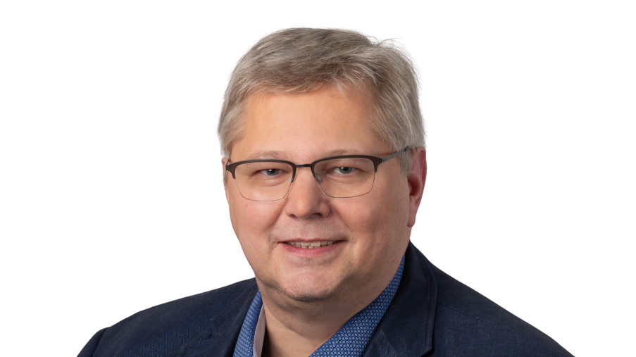 Regionalleitung Andreas Trümper, lächelnd mit Brille und dunklem Jackett vor einem hellen Hintergrund